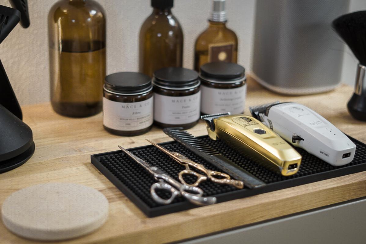 Mace & Co styling products, scissors and clippers arranged at a barber station